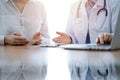 Doctor and patient discussing something while using laptop computer and sitting near each other at the wooden desk in Royalty Free Stock Photo