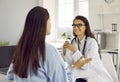 Friendly female doctor listening to her female patient at consultation meeting in hospital office. Royalty Free Stock Photo