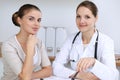 Doctor and patient having a pleasure talk while sitting at the desk at hospital office. Healthcare and medicine concept Royalty Free Stock Photo