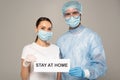 Doctor and patient holding card with stay at home lettering