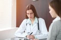 Doctor and patient in hospital. Physician filling up medication history records while talking with young woman