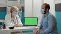 Doctor and patient looking at laptop with greenscreen