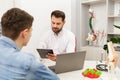 Doctor and patient in medical office. Therapist talking to patient in office, taking notes, writing prescription Royalty Free Stock Photo