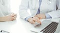 Doctor and patient sitting near each other at the desk in clinic. The focus is on female physician& x27;s hands using Royalty Free Stock Photo