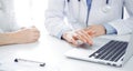 Doctor and patient sitting near each other at the desk in clinic. The focus is on female physician& x27;s hands using Royalty Free Stock Photo