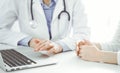 Doctor and patient sitting near each other at the desk in clinic. The focus is on female physician& x27;s hands using Royalty Free Stock Photo