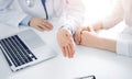 Doctor and patient sitting near each other at the desk in clinic. The focus is on female physician& x27;s hands using Royalty Free Stock Photo