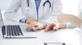 Doctor and patient sitting near each other at the desk in clinic. The focus is on female physician& x27;s hands using Royalty Free Stock Photo