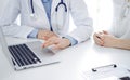 Doctor and patient sitting near each other at the desk in clinic. The focus is on female physician& x27;s hands using Royalty Free Stock Photo