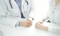 Doctor and patient sitting near each other at the desk in clinic. The focus is on female physician& x27;s hands using Royalty Free Stock Photo