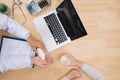 Doctor and patient talking while sitting at the desk in office. Physician pointing into medical history form. Medicine and health Royalty Free Stock Photo