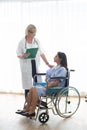 Doctor and patient woman sitting on wheelchair discussing something healthcare in room of hospital. Royalty Free Stock Photo