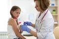 Doctor pediatrician holding syringe with injection vaccination. Girl is afraid.