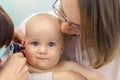 Doctor pediatrist examining childs ear with otoscope. Mom holding baby with hands. Medicine, healthcare ,pediatry and Royalty Free Stock Photo