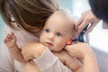 Doctor pediatrist examining childs ear with otoscope. Mom holding baby with hands. Medicine, healthcare ,pediatry and Royalty Free Stock Photo