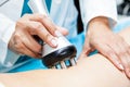 Doctor performing a radiofrequency treatment on a female patient leg