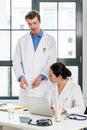 Doctor and pharmacist checking information on a laptop in a modern hospital