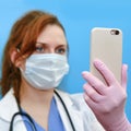 Doctor with a phone in her hand, blue background. Concept of remote care for patients with coronavirus, helps patients through the