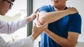 Doctor physiotherapist assisting a male patient while giving exercising treatment massaging the arm of patient in a physio room, Royalty Free Stock Photo