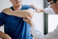 Doctor physiotherapist assisting a male patient while giving exercising treatment massaging the arm of patient in a physio room,