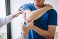 Doctor physiotherapist assisting a male patient while giving exercising treatment massaging the arm of patient in a physio room, Royalty Free Stock Photo