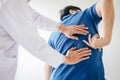 Doctor physiotherapist treating lower back pain patient after while giving exercising treatment on stretching in the clinic,