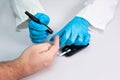 Doctor piercing patients finger with lancet in clinic closeup. Blood glucose control concept