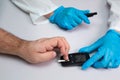 Doctor piercing patients finger with lancet in clinic closeup. Blood glucose control concept