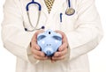 Doctor With Piggy Bank In Both Hands