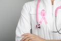 Doctor with pink ribbon and stethoscope on grey background. Breast cancer awareness Royalty Free Stock Photo