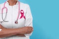 Doctor with pink ribbon and stethoscope on light blue background, closeup and space for text. Breast cancer awareness Royalty Free Stock Photo