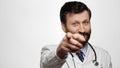Doctor points his finger to you. Smiling kind man doctor on white background looking at camera and points his finger in