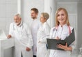Doctor posing, smiling, while medical staff standing behind. Royalty Free Stock Photo