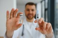 Doctor in PPE holding a vial or bottle vaccine against coronavirus Covid 19 new Omicron variant or strain in his hand, close up. Royalty Free Stock Photo