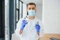 Doctor in PPE holding a vial or bottle vaccine against coronavirus Covid 19 new Omicron variant or strain in his hand, close up. Royalty Free Stock Photo