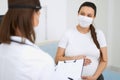 Doctor and pregnant woman wearing mask during examination