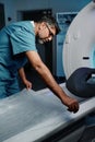 Doctor Preparing CT Scanner Bed For Next Patient
