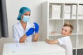 The doctor is preparing to vaccinate the child against the coronavirus. The boy turned around, looked at the camera and smiled. Royalty Free Stock Photo