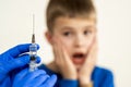 Doctor preparing vaccination injection with a syringe to an afraid child boy. Vaccination of children at school concept Royalty Free Stock Photo