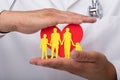 Doctor protecting heart with family figures Royalty Free Stock Photo