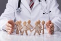 Doctor Protecting Wooden Figures Royalty Free Stock Photo