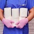 A doctor in protective gloves holds rolls of toilet paper. Lots of rolls of white toilet paper, diarrhea concept