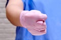 Doctor in protective gloves shows a vulgar gesture of a fig sign, closeup