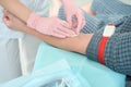 Doctor in protective gloves takes blood from a patient