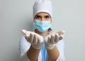 Doctor in protective mask and medical gloves against light grey background, focus on hands Royalty Free Stock Photo