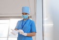 Doctor in protective mask and scrubs putting on medical gloves indoors. Space for text Royalty Free Stock Photo