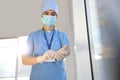 Doctor in protective mask and scrubs putting on medical gloves. Space for text Royalty Free Stock Photo