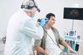 Otorhinolaryngologist examining male with medical instrument at the hospital