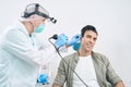 Otorhinolaryngologist examining man with medical instrument at the hospital