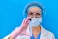 A doctor in protective medical clothing from viruses holds a test tube for analysis, blue background. Nurse in a medical mask with
